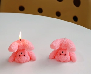 Detail of pink teddy dog scented candles showing lit and unlit states on table