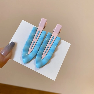 Detail showing wavy textured hair clips in light blue and pink on white card