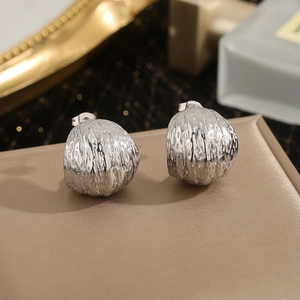 Textured silver hemispherical earrings with irregular hammered finish on display
