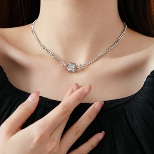 Gros plan d'un collier carré argenté avec pierre centrale porté par un mannequin