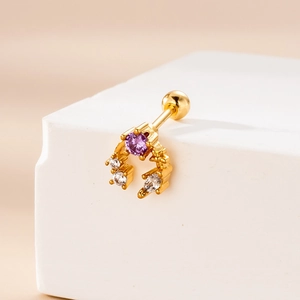 Detailed close-up of golden stainless steel piercing stud with purple zircon and tiny diamonds