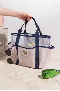 Close-up of a white mesh beach bag featuring Beach Love patch and blue straps