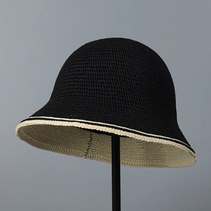 Close-up of knit bucket hat showing dense black texture and cream white brim trim detail