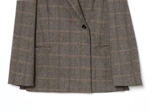 Close-up of herringbone tweed blazer featuring a subtle plaid pattern and pocket detail