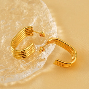 Detail view of gold layered hoop earrings on champagne silk showing smooth metal texture