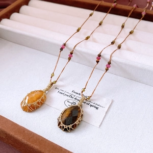 Macro shot of handmade beaded necklace featuring tiger eye and orange jade stone charms