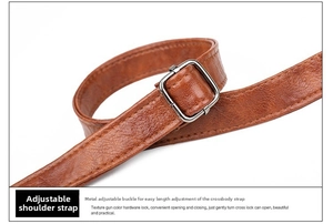 Gros plan d'une bandoulière en cuir grainé marron avec boucle en métal gris fusil