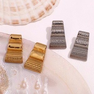 Detailed close-up of trapezoid wave-pattern earrings with water droplets on shell