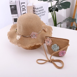 Detailed view of straw sun hat and matching bag with lace trim and pink fabric flowers
