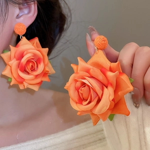 Detail of large orange fabric rose earrings with gradient petals and gold metal link