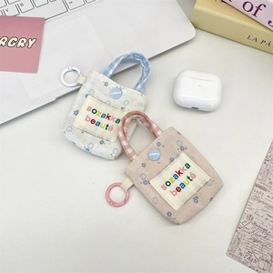 Close-up of floral mini earphone cases with button closure and snap hooks on a desk