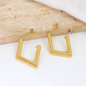 Minimalist gold geometric square earrings with spiral texture on marble stone background