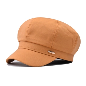 Detail of yellow newsboy cap with cotton twill texture and gold metal decorative plate