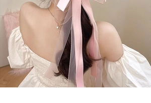 Close-up of pink layered bow hair clip with pearls on wavy brown hair style