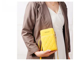 Detail of bright yellow phone bag with quilted diamond pattern and butterfly embroidery