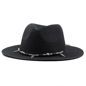 Detail of black woven sun hat with ethnic style beaded band and metal feather pendant