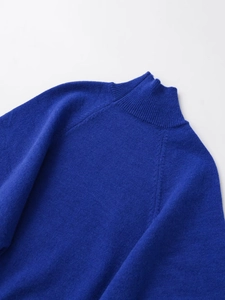 Détail du col montant bleu et des manches raglan sur un pull en maille douce