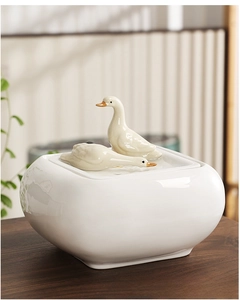 Detail of creative white ceramic water fountain featuring two delicate duck figurines