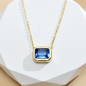 Detail of blue rectangular zircon pendant with minimalist gold plated stainless steel chain