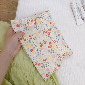 Detailed shot of a floral fabric makeup bag with red and yellow flowers held by a hand