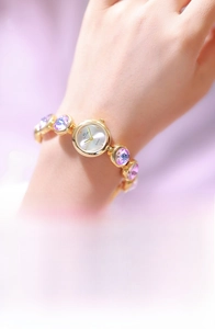 Détail de la montre dorée pour femme avec bracelet serti de pierres violettes au poignet