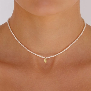 Detail of S925 silver necklace with white pearls and gold Hamsa Hand pendant on model