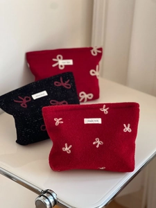 Three felt makeup bags in red and black with elegant bow embroidery and simple labels