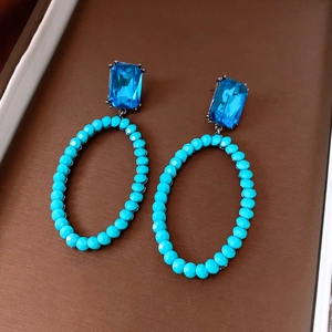 Macro shot of vintage style earrings with blue crystal beads and large oval hollow pendants