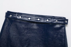 Détail rapproché d'une mini-jupe en similicuir bleu foncé avec ceinture et boucles argentées