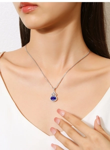 Detail of S925 silver gourd necklace with blue emerald pendant worn on model's neck