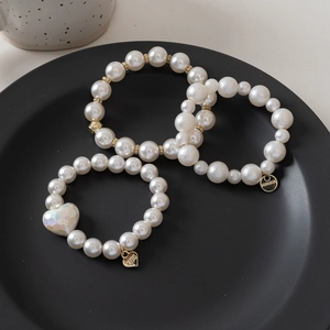 Detailed shot of three pearl hair ties featuring gold heart pendants and cute charms