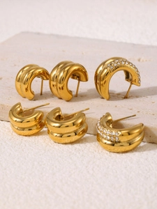 Close-up of gold double-layer C-shape earrings with rhinestones on stone background