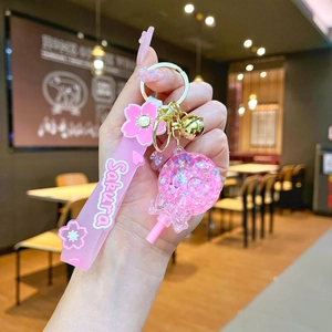 Close-up of pink Sakura liquid sand keychain with silicone wristband and golden bell