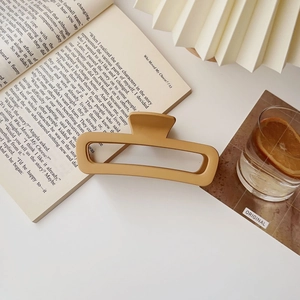 Dettaglio della molletta rettangolare giallo senape opaco su un libro in un set morbido