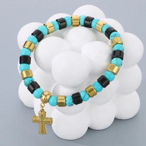 Détail du bracelet en perles de turquoise bleu ciel avec pendentif croix dorée sur support
