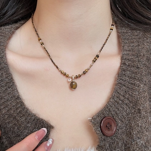 Detail of tiger eye stone necklace with gold plating and zircons on female model