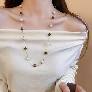 Detail of beaded necklace with tiger eye stones and pearls on a shoulder-off model