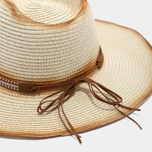 Detailed macro view of woven straw texture with rhinestone-studded brown leather band