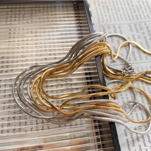 Detailed close-up of gold and silver snake chain necklaces with metallic texture