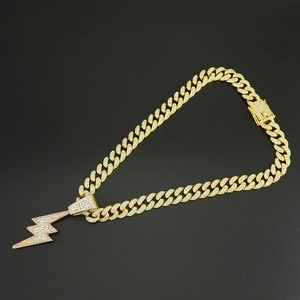 Detail of gold Cuban chain necklace with sparkling pink and clear lightning bolt pendant