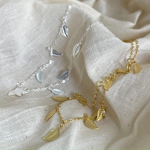 Minimalist 925 sterling silver leaf anklets in gold and silver finishes on white linen