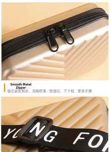 Detail of champagne gold mini suitcase bag with dual zippers and logo woven shoulder strap