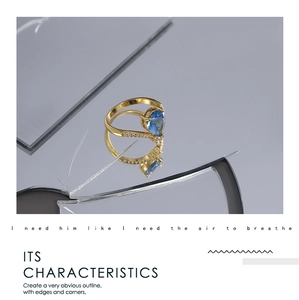 Detailed view of a gold ring with a pear-cut blue gemstone on a broken mirror surface