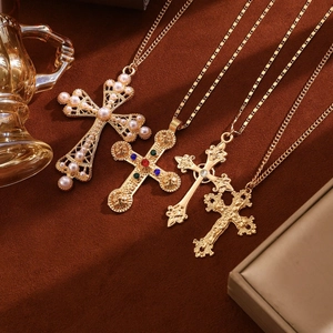 Detail view of four gold cross necklaces with pearls and colorful gems on brown velvet