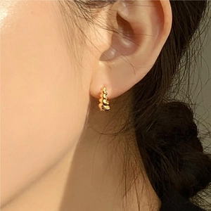 Close-up of gold textured mini hoop earrings worn by a model for a stylish look