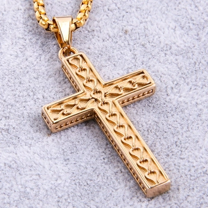Detailed view of a golden cross pendant with heart cut-outs and a matching box chain