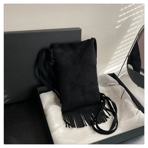 Detail of black fringe suede crossbody bag presented in an elegant silk-lined gift box