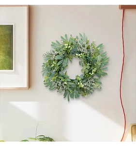 Detailed view of an artificial eucalyptus wreath with white berries on a beige wall