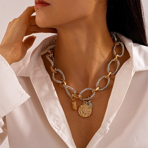 Dettaglio della collana vintage bicolore con ciondolo a moneta sul collo di una modella