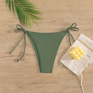 Close-up of olive green side-tie bikini bottoms on a light wood background